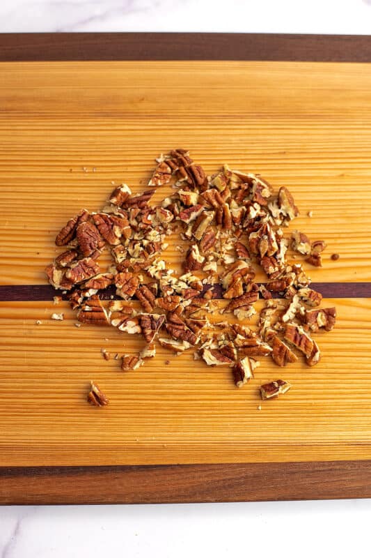 Chopped pecans on a wood cutting board.