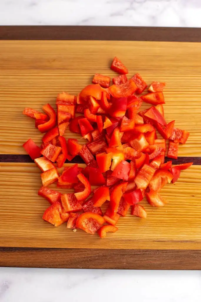 Chopped red bell pepper on wood cutting board.