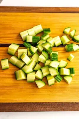 Cucumbers chopped up on a cutting board for Mediterranean tomato cucumber salad.