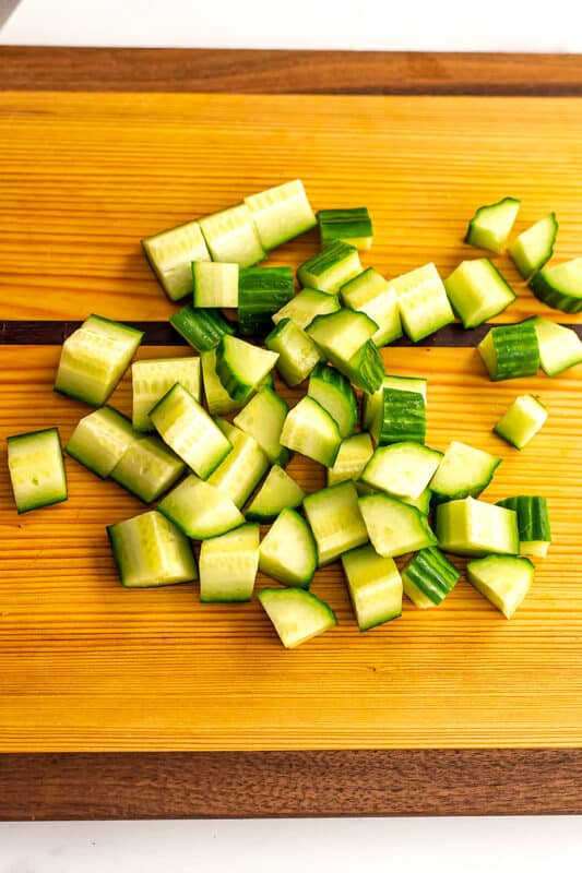 Cucumbers chopped up on a cutting board for Mediterranean tomato cucumber salad.