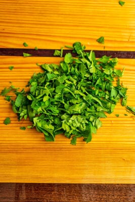 Finely chopped parsley on wood cutting board.
