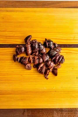 Finely chopped kalamata olives on wood cutting board.