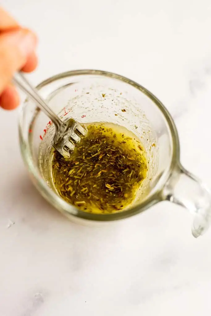 Lime vinaigrette dressing in a glass measuring cup after stirring.