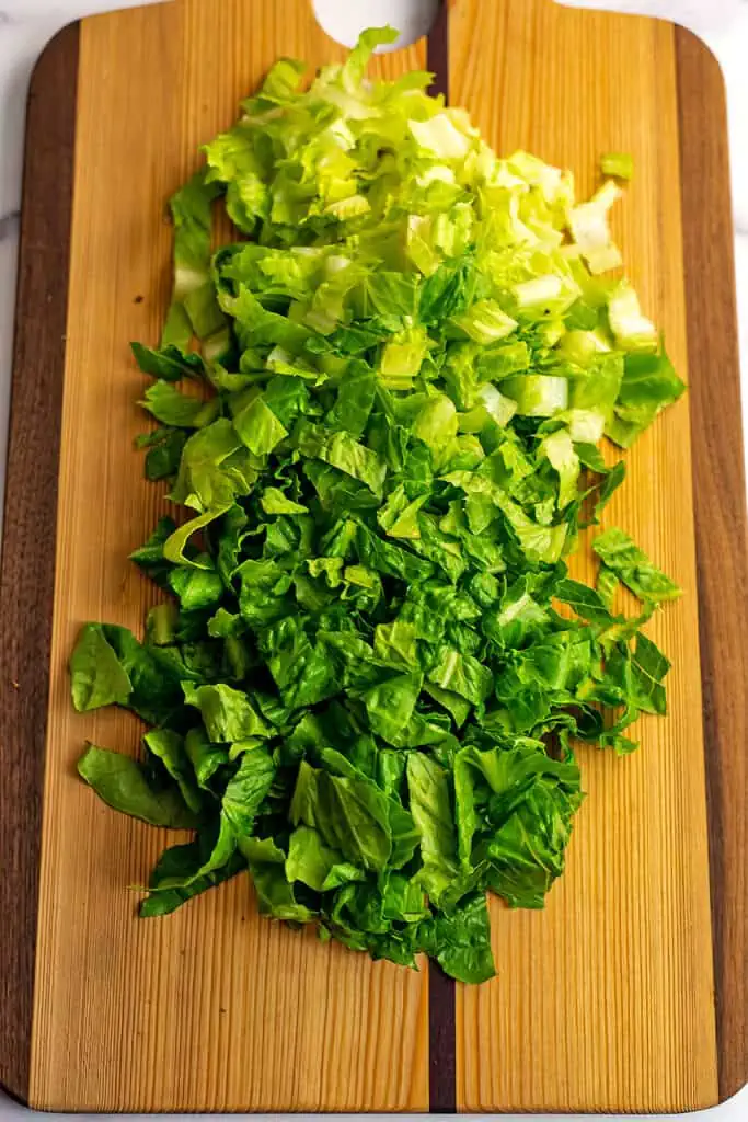 Chopped romaine lettuce on a wood cutting board.