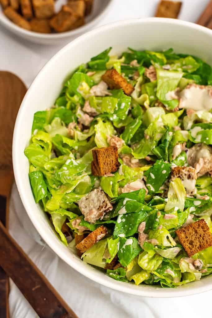 Tuna caesar salad in white bowl.