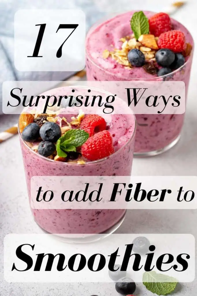 Two smoothies sitting on a white table with raspberries, blueberries and granola on top.