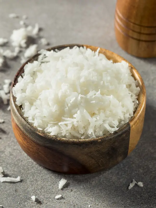 A bowl of coconut flakes used in smoothies for added flavor and fiber.