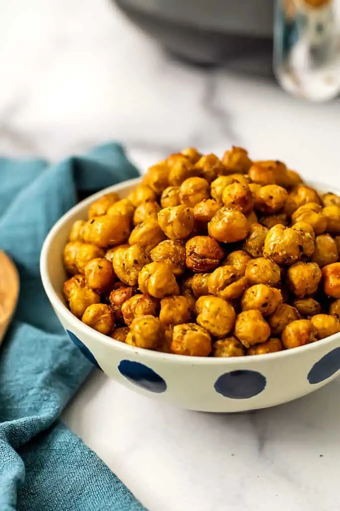 Air fryer roasted chickpeas in a white bowl next to a blue napkin. 