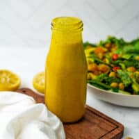 Turmeric dressing on a white table next to a salad.