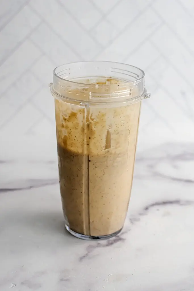 Banana cinnamon smoothie blended in a large blender cup.