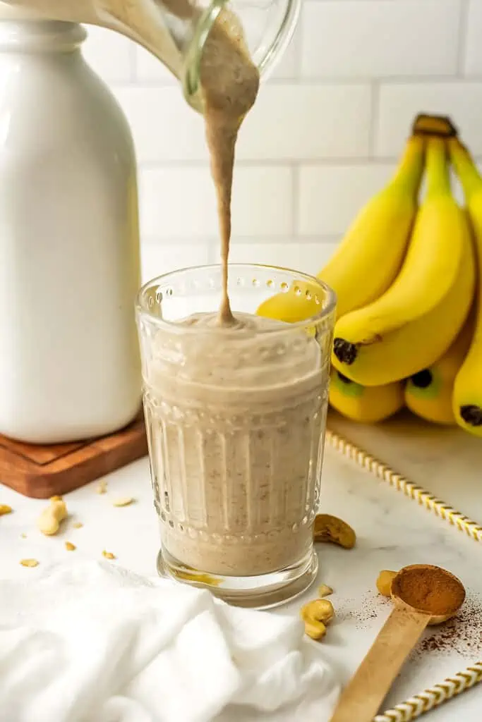 Banana cinnamon smoothie being poured into a glass.