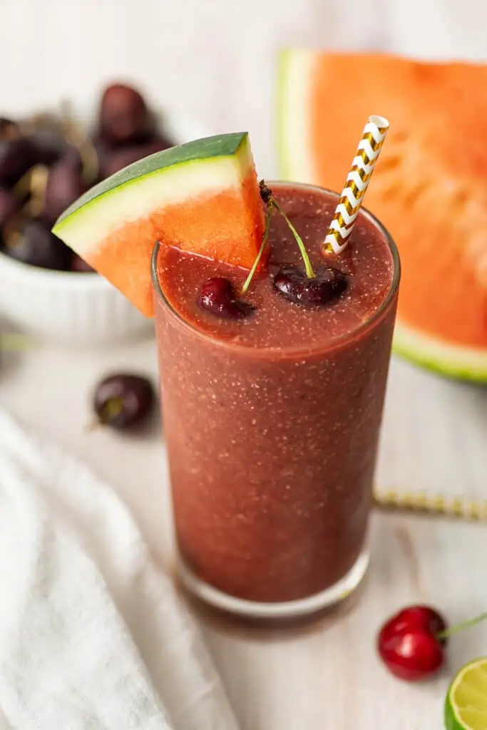 Cherry watermelon smoothie with sliced watermelon and fresh cherries on top.