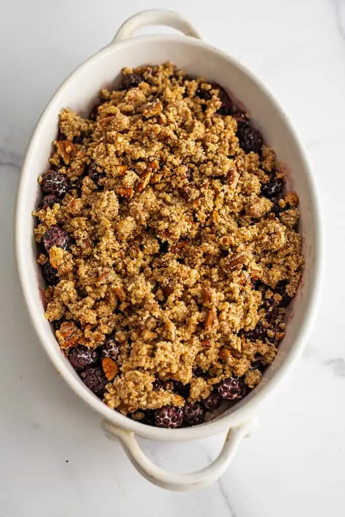 Pecan and almond flour mixture on top of blueberries in a white casserole dish.