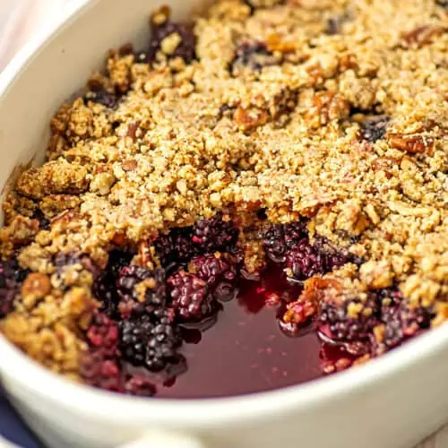 Gluten free blackberry crumble in a white ceramic baking dish.