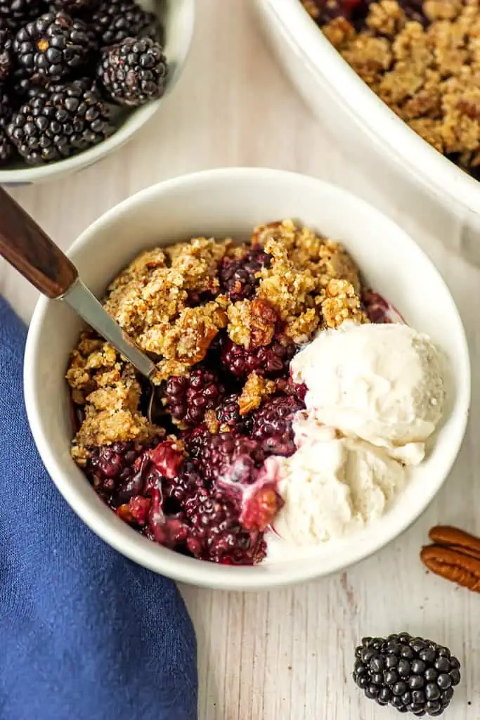 Gluten free blackberry crumble in a bowl with ice cream.