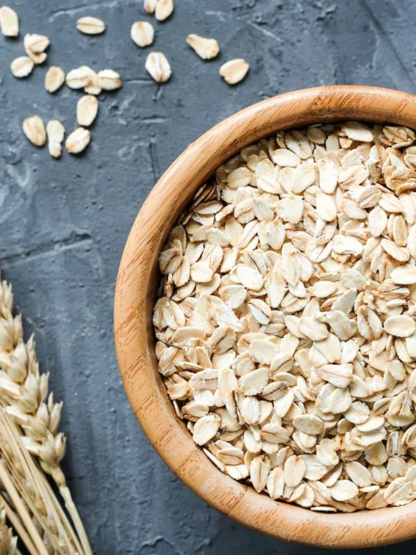 A bowl of oatmeal in a wooden bowl on a dark surface.