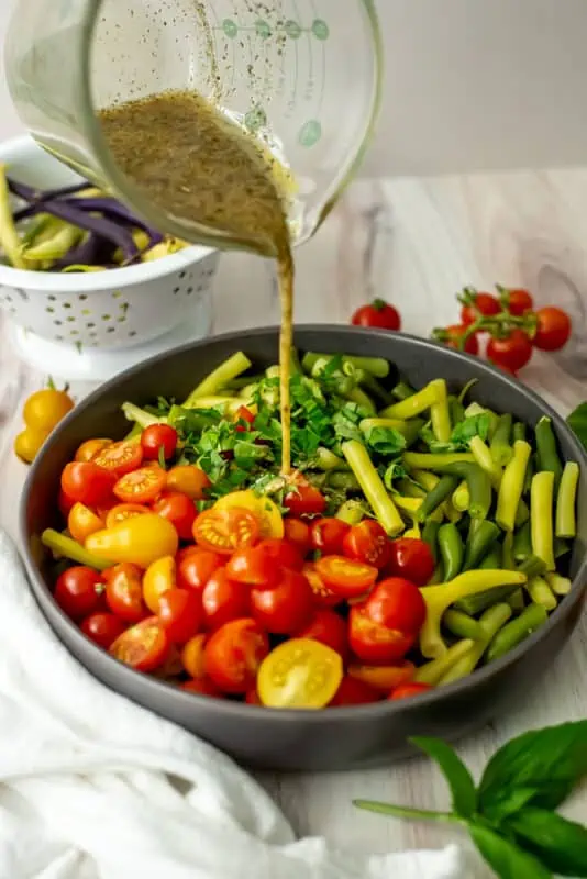 Italian green bean salad with dressing being poured on.
