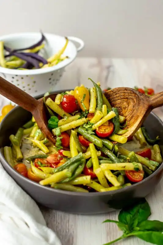 Italian green bean salad being mixed in a gray bowl.