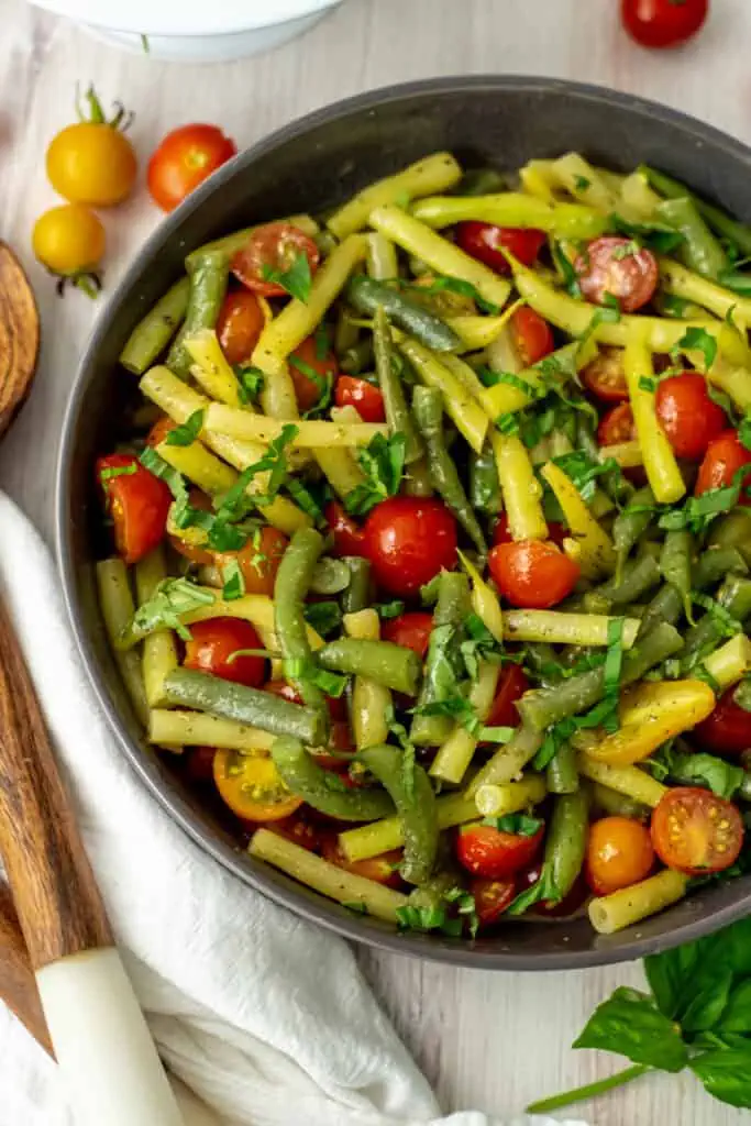 Italian green bean salad in a large gray bowl sitting on a white table clothe.