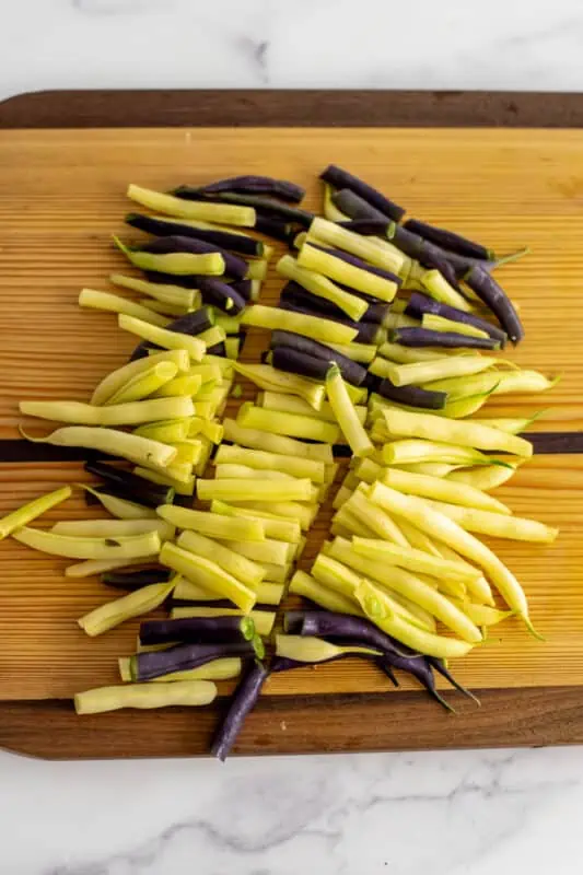Beans cut into bite size pieces on wood cutting board.