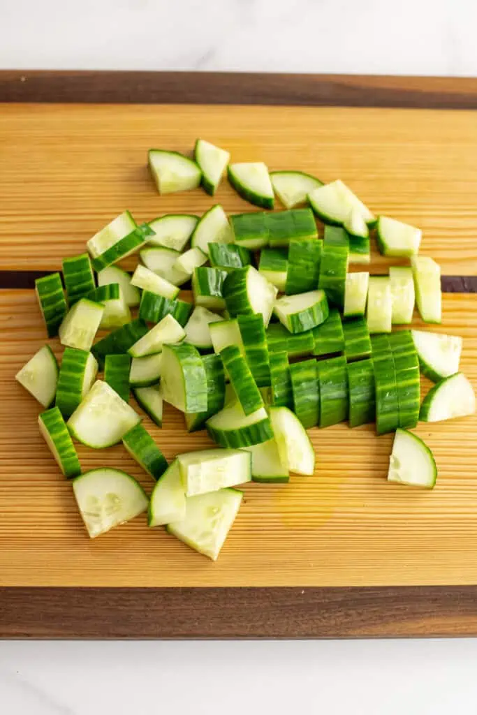 Cucumbers thinly sliced on a cutting board.
