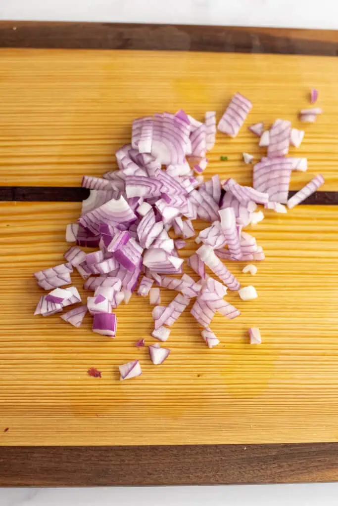 Red onion finely chopped on a wooden cutting board.