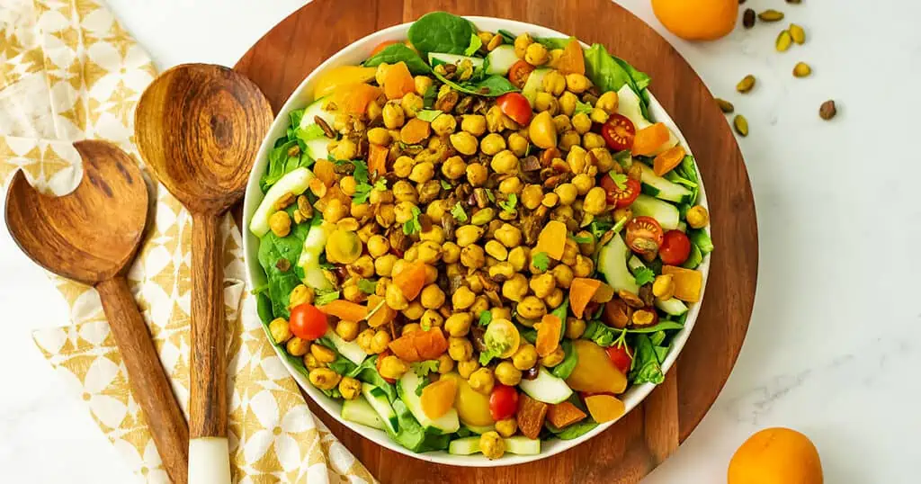A chickpea salad on a wooden serving tray.