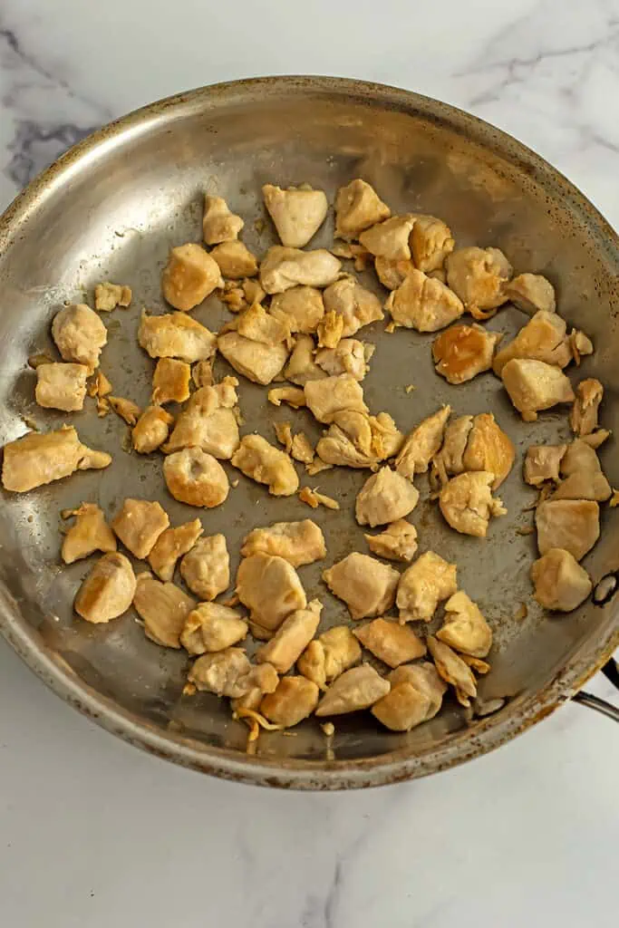 Chicken cubes fully cooked in a stainless steel skillet.