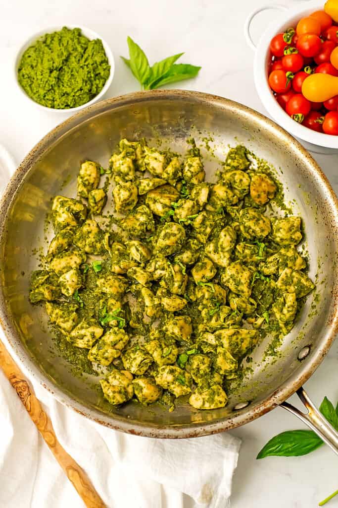 pesto chicken cooked up in a stainless steel skillet.