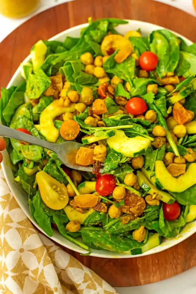 Spinach chickpea salad in a small salad bowl with a fork.
