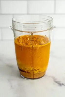 Turmeric dressing ingredients in a blender cup before being blended.