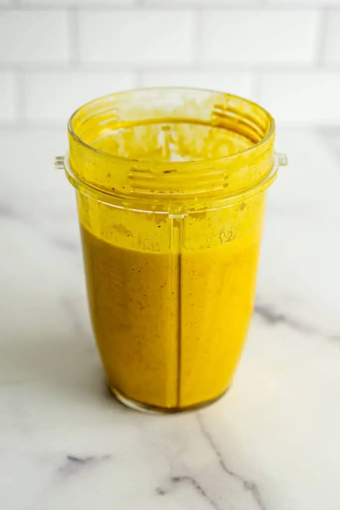 Turmeric dressing in a blender cup after being blended.