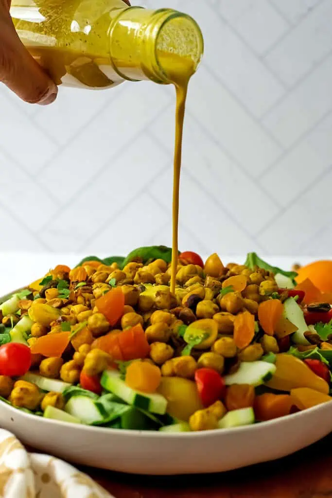 Turmeric dressing being poured over a salad.