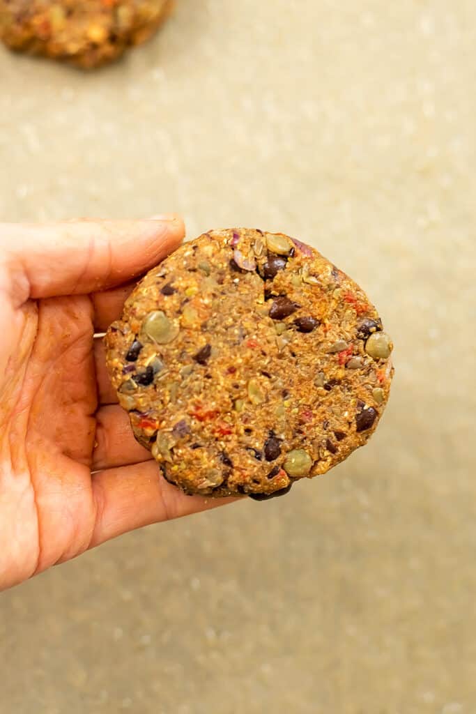 Hand holding black bean lentil burger.