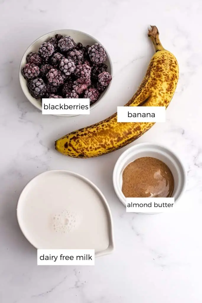 Blackberry banana smoothie ingredients separated into white ramekins and a banana.
