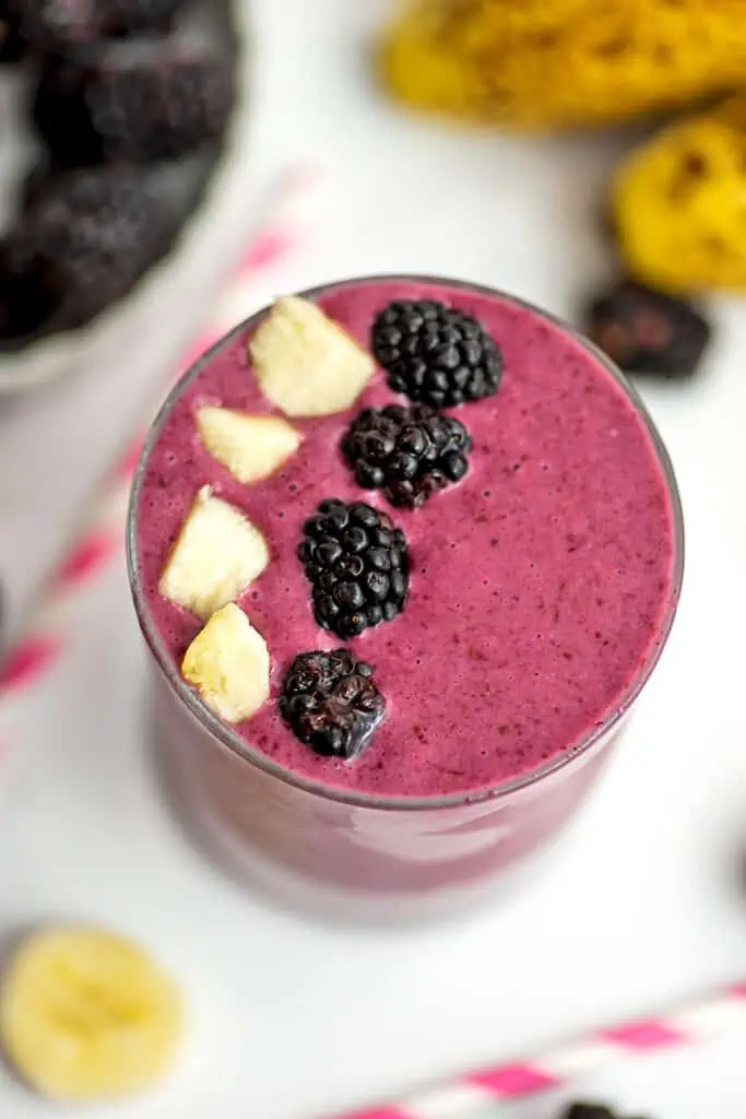 Blackberry banana smoothie with cut pieces of banana and blackberries lined across on top of the smoothie.