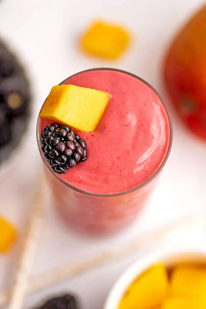 Mango blackberry smoothie with pieces of mango and blackberry on top.