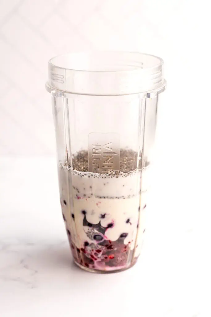 Blueberry raspberry smoothie ingredients in a blender cup before being blended.