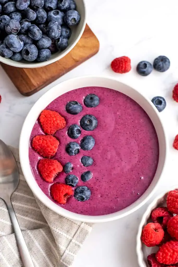 A raspberry blueberry smoothie bowl with raspberries and blueberries on top.