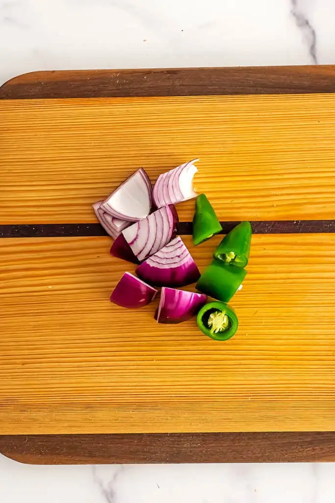Red onion and jalapeno on a wooden cutting board.