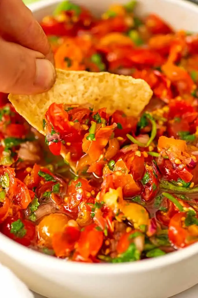 A chip being dipped into cherry tomato salsa.