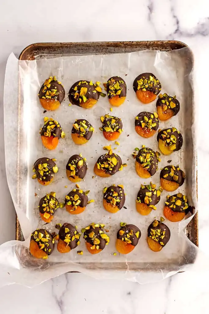 Chocolate covered apricots on a baking sheet after freezing.