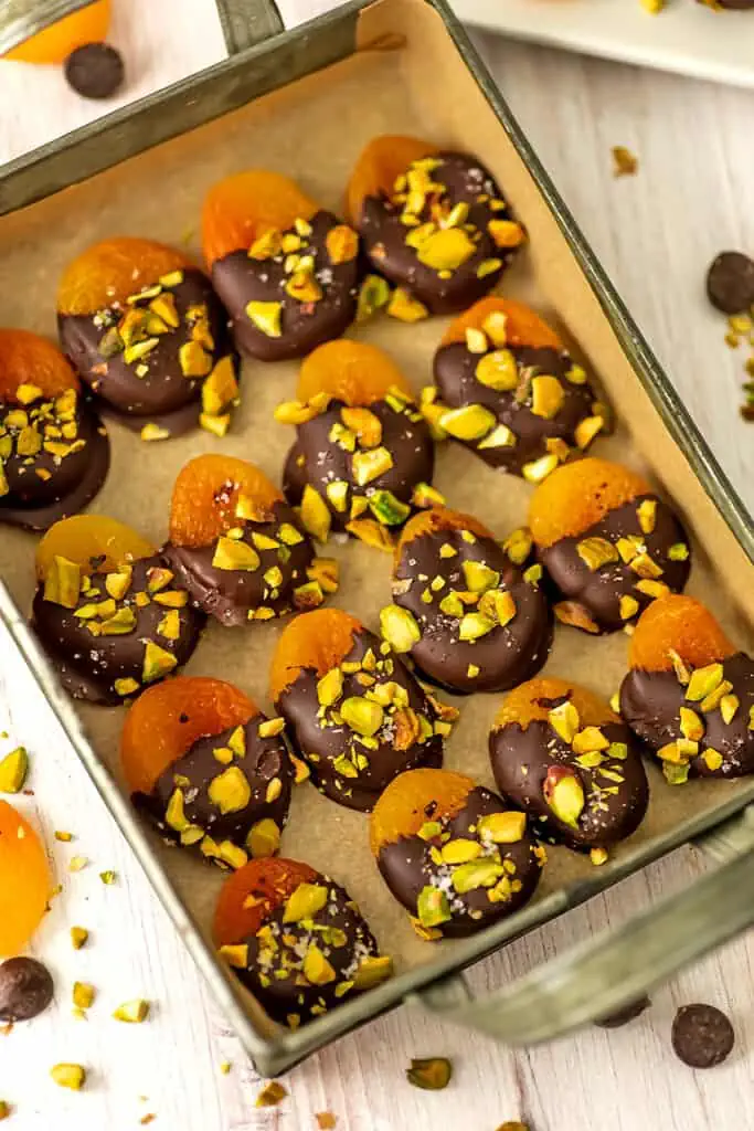 Dark chocolate dipped apricots on a serving tray.
