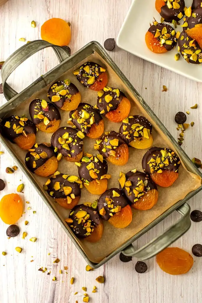 Chocolate covered apricots with pistachios on a serving tray.