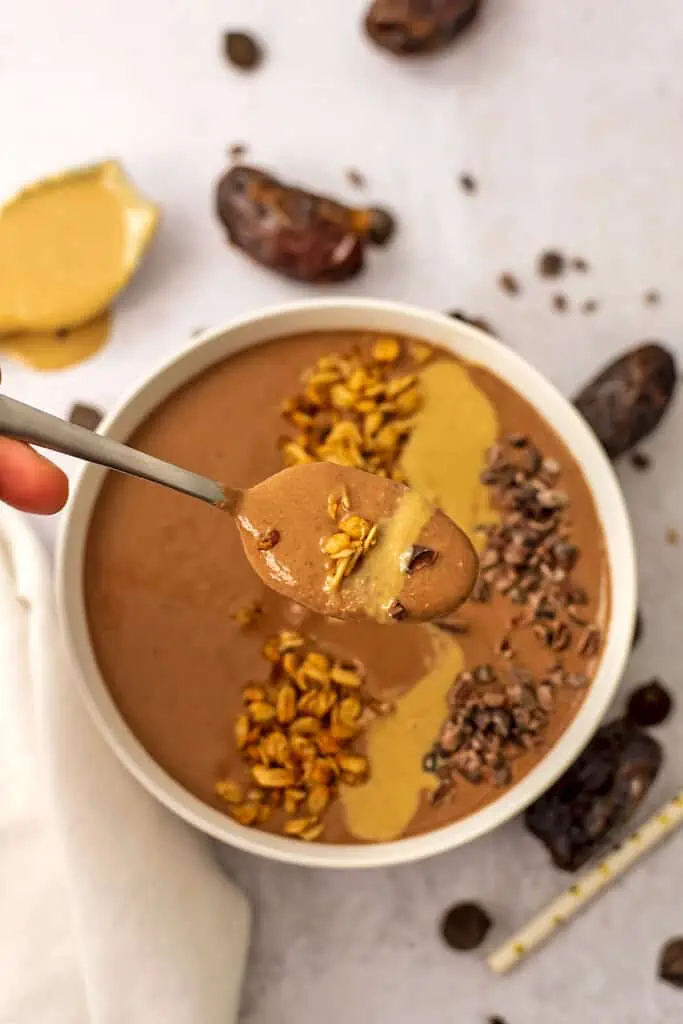 Chocolate Tahini Smoothie in a smoothie bowl with granola, cacao nibs and tahini drizzled on top. 
