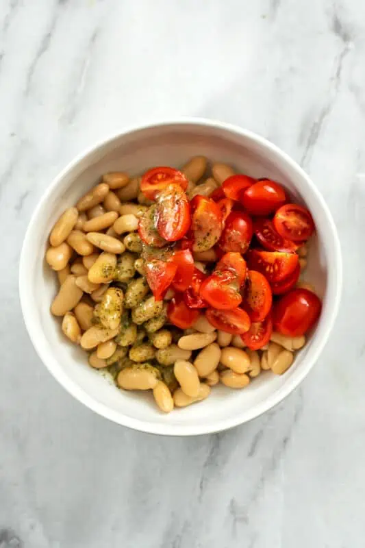 White beans, tomatoes and dressing in a bowl.