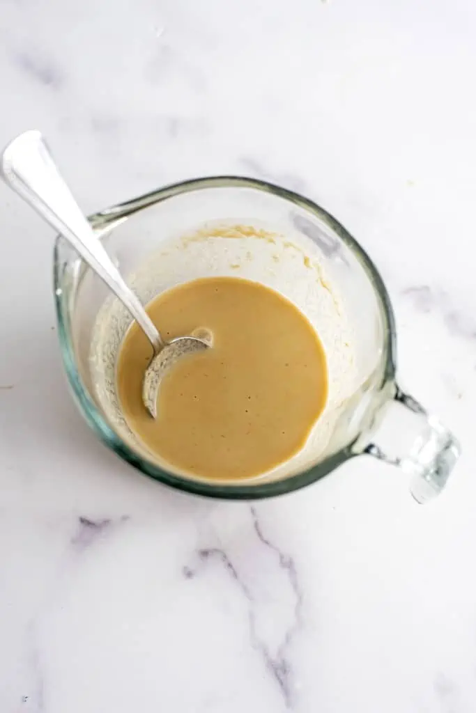 Tahini dressing stirred together in a measuring cup.