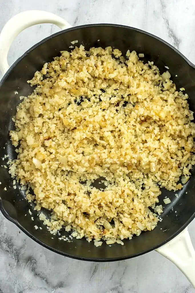 Cooked cauliflower rice in cast iron skillet. 