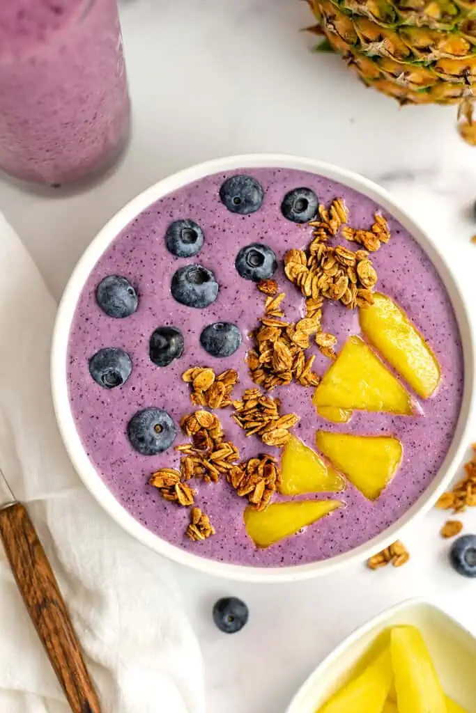 A pineapple blueberry smoothie bowl with blueberries, pineapple chunks and granola topping the smoothie bowl.
