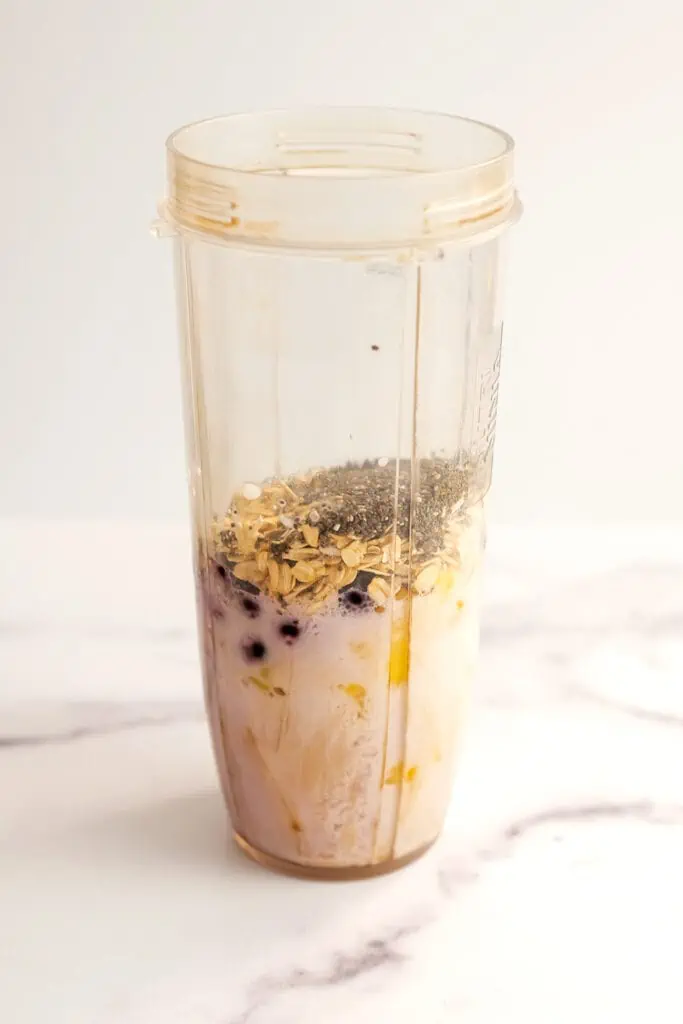 Pineapple blueberry smoothie ingredients added to a blender cup before being blended.